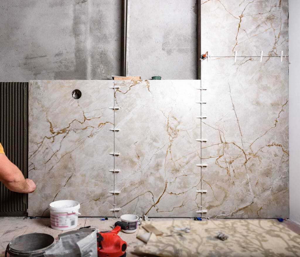 Tiler installing leveling system tiles on wall.